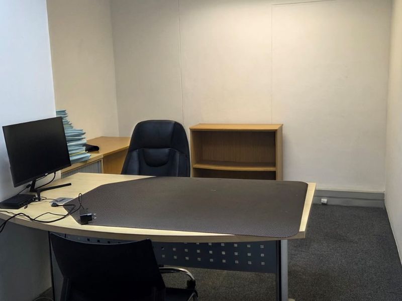 A functional office space featuring carpeted flooring and a glass partition wall, providing a professional environment for work.