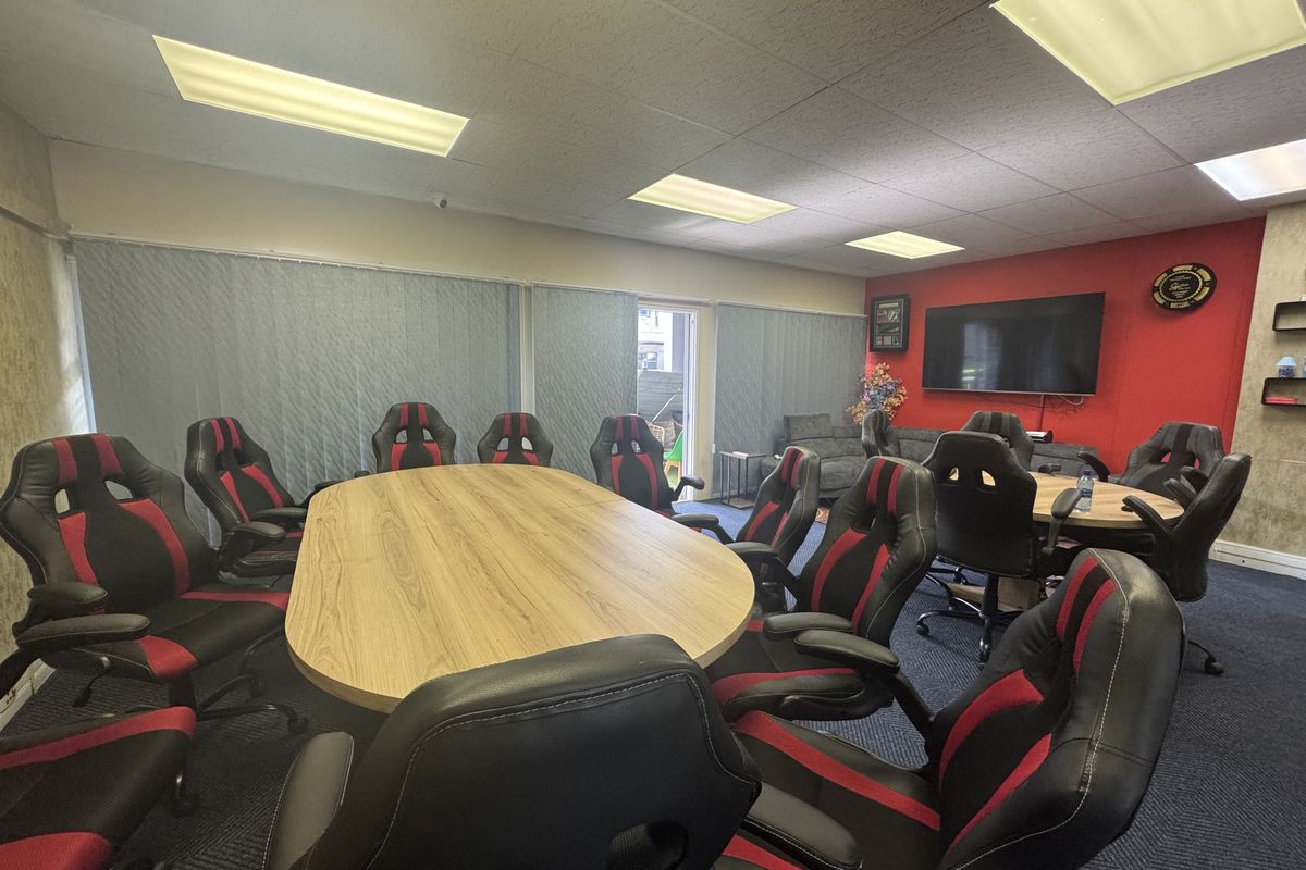 A functional office space featuring acoustic ceiling tiles, recessed lighting, and carpet flooring, currently configured as a meeting room.