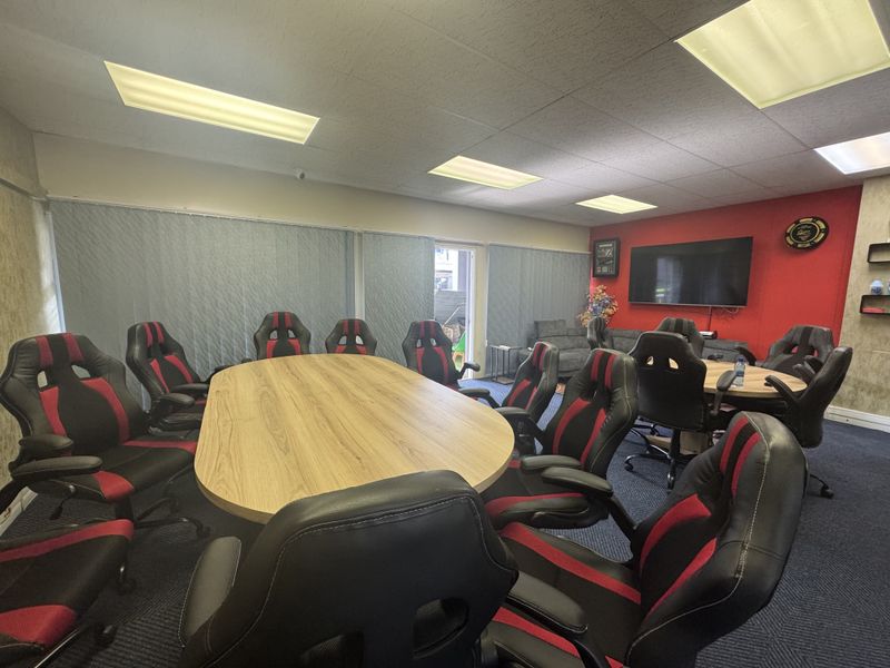 A functional office space featuring acoustic ceiling tiles, recessed lighting, and carpet flooring, currently configured as a meeting room.