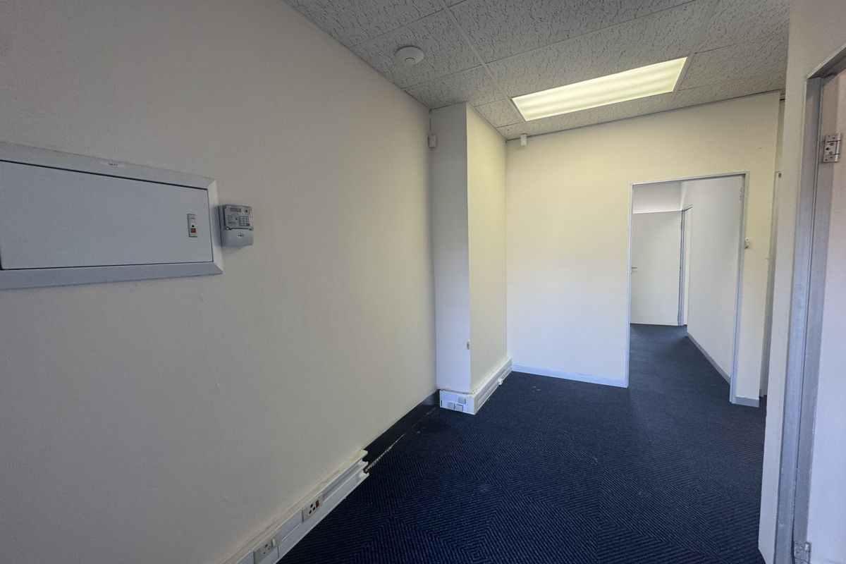 Empty office space featuring carpeted flooring, suspended ceiling with recessed lighting, and integrated electrical trunking for workstation connectivity.