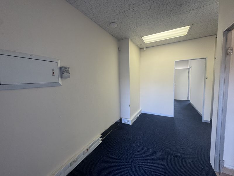 Empty office space featuring carpeted flooring, suspended ceiling with recessed lighting, and integrated electrical trunking for workstation connectivity.