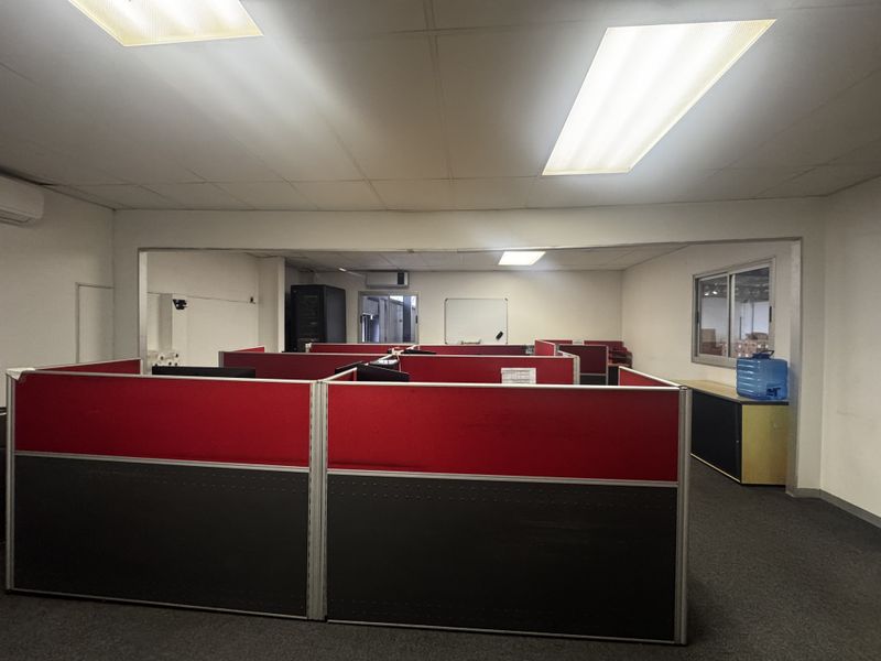 Open-plan office space featuring modular partitions, suspended ceilings with recessed lighting, carpeted flooring, and integrated air conditioning.