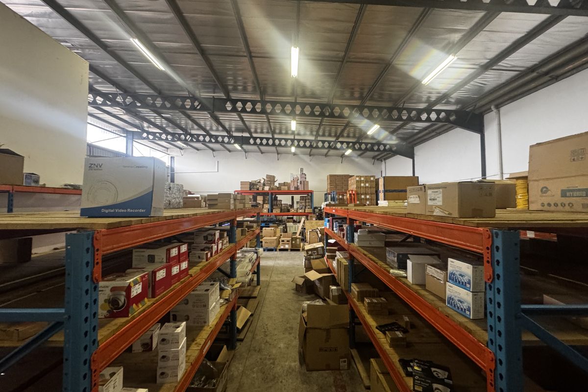 Industrial warehouse storage area featuring heavy-duty steel racking systems, exposed roof trusses, and concrete flooring, suitable for logistics or inventory management.