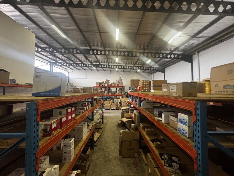 Industrial warehouse storage area featuring heavy-duty steel racking systems, exposed roof trusses, and concrete flooring, suitable for logistics or inventory management.
