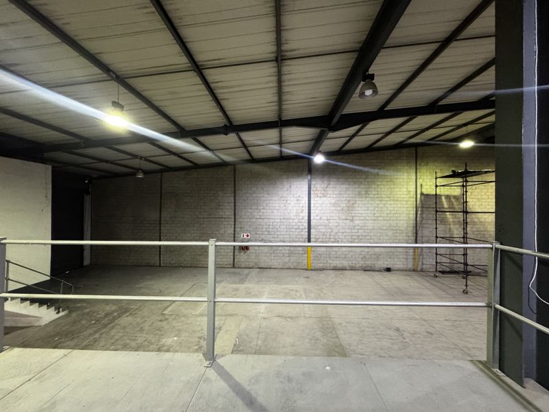 Spacious industrial utility area featuring exposed steel roof trusses, concrete flooring, and brick walling, suitable for storage or workshop use.