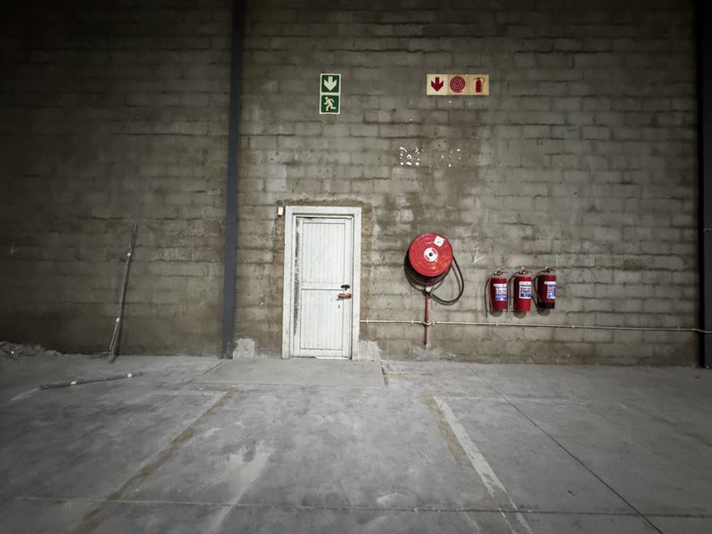 Industrial utility space featuring exposed blockwork walls, concrete flooring, and essential fire safety equipment including a hose reel and extinguishers.