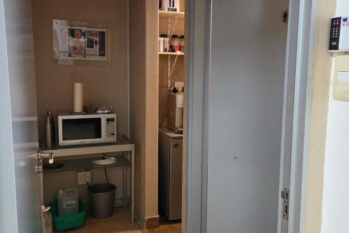 A compact utility or kitchenette area featuring built-in shelving, wall-mounted security controls, and climate control thermostat.