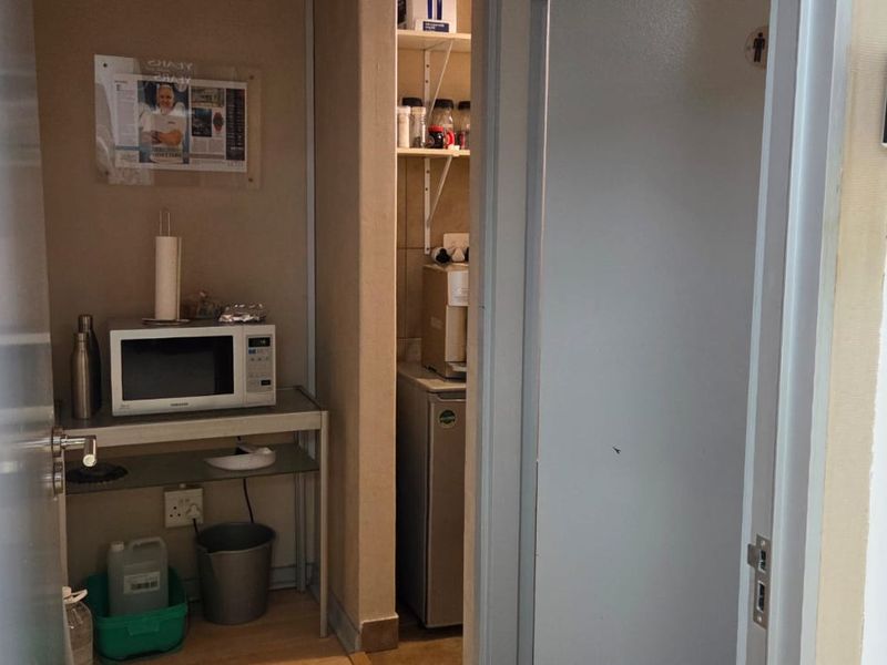 A compact utility or kitchenette area featuring built-in shelving, wall-mounted security controls, and climate control thermostat.