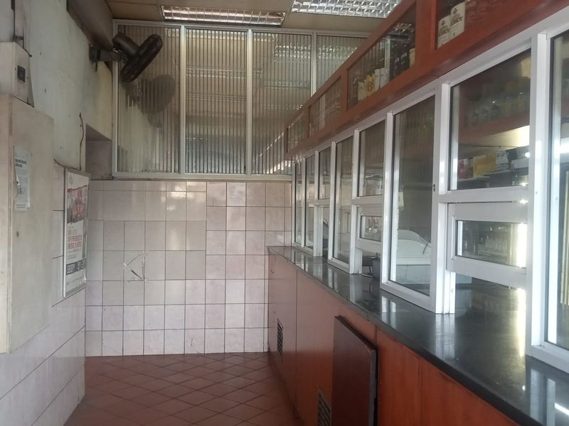 A functional retail bar area featuring built-in cabinetry, tiled wall finishes, and a service counter, suitable for commercial refreshment or retail operations.