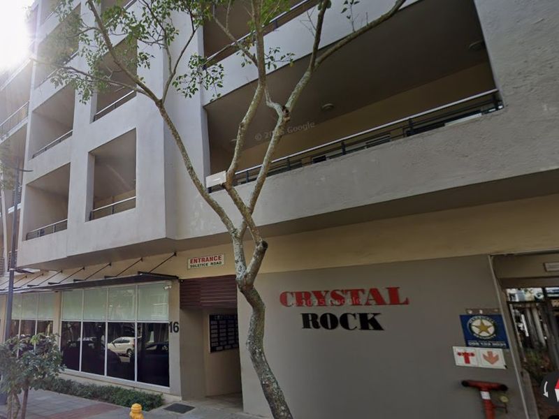 Front exterior view of the Crystal Rock office building, featuring a modern facade with balconies, large windows, and clear street-level entrance signage.