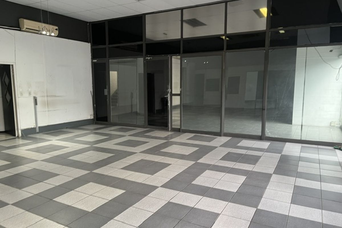 Spacious industrial office area featuring tiled flooring, glass partitioning, and a suspended ceiling with integrated lighting.