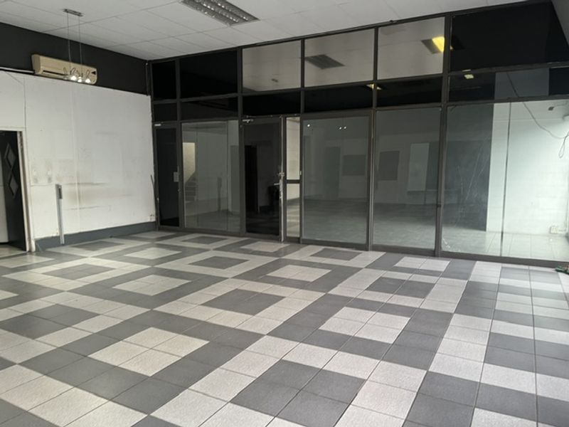 Spacious industrial office area featuring tiled flooring, glass partitioning, and a suspended ceiling with integrated lighting.