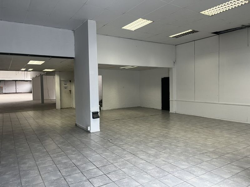 Spacious open-plan industrial unit featuring ceramic tiled flooring, suspended ceilings with recessed lighting, and neutral painted walls, suitable for various commercial or retail uses.