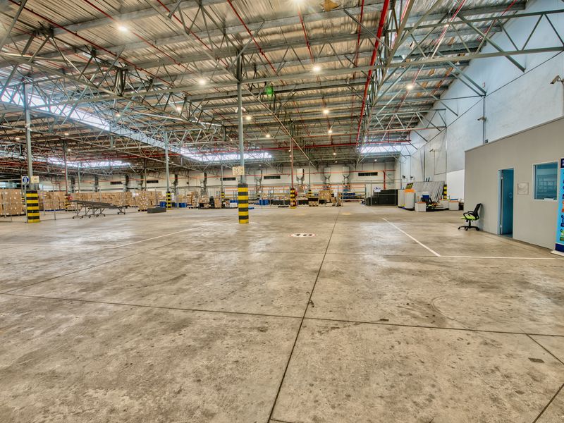 Spacious industrial warehouse featuring high-clearance exposed steel truss ceilings, polished concrete flooring, and integrated fire sprinkler systems.