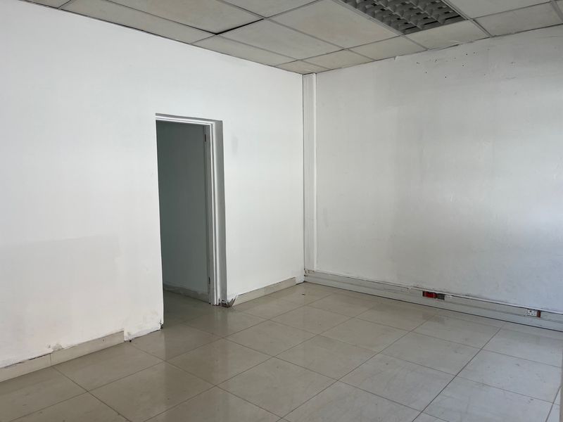 An empty office space featuring tiled flooring, a suspended ceiling with recessed lighting, and perimeter electrical trunking.