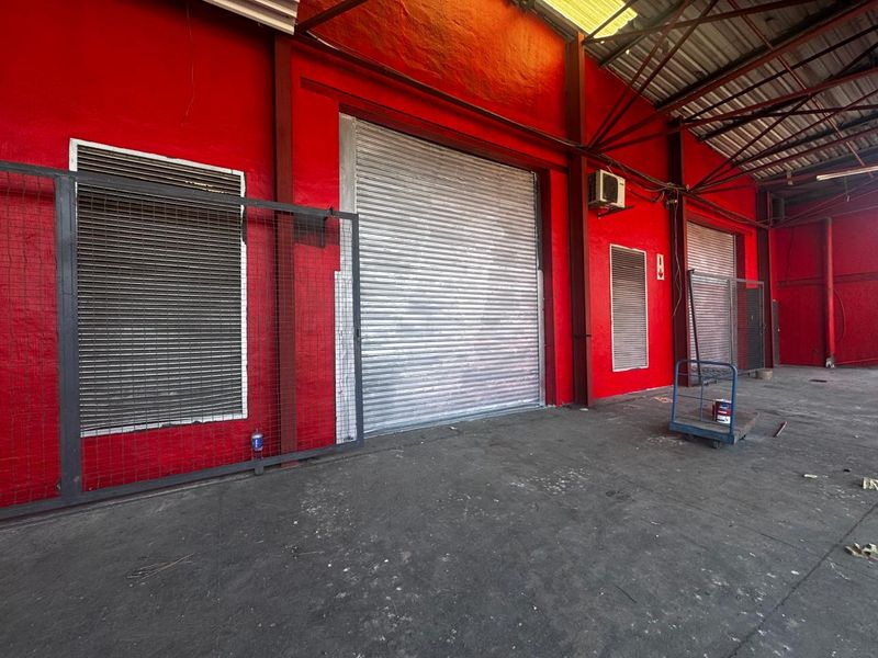 Industrial warehouse space featuring high ceilings, concrete flooring, and multiple roller shutter doors for efficient loading and access.