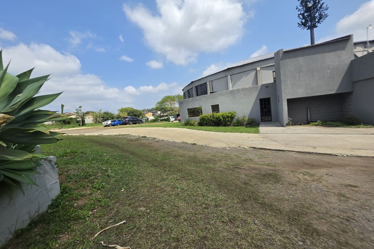 Exterior view of a commercial property featuring a concrete driveway, landscaped grounds, and a prominent cell tower structure.