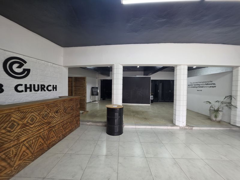 Spacious commercial entry area featuring a built-in reception desk, tiled flooring, and structural columns, suitable for a welcoming reception or lobby space.