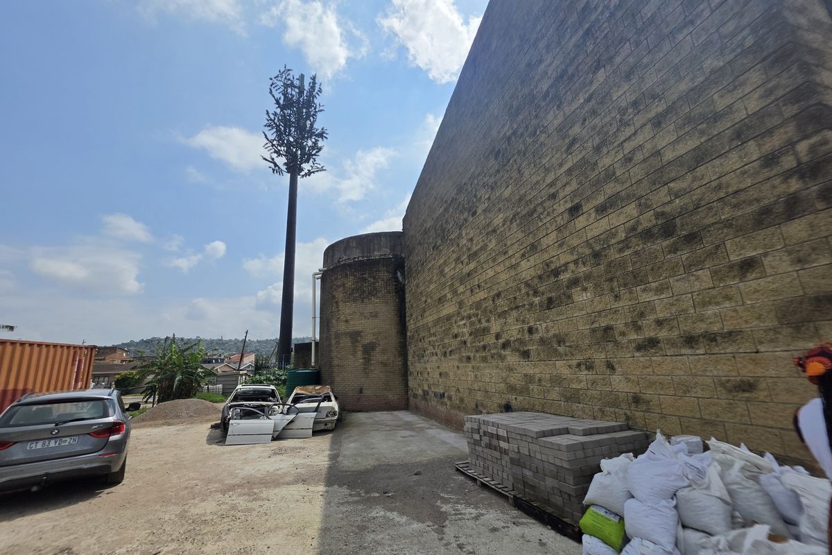 Rear exterior view of the commercial property featuring a large brick facade and an adjacent telecommunications tower.