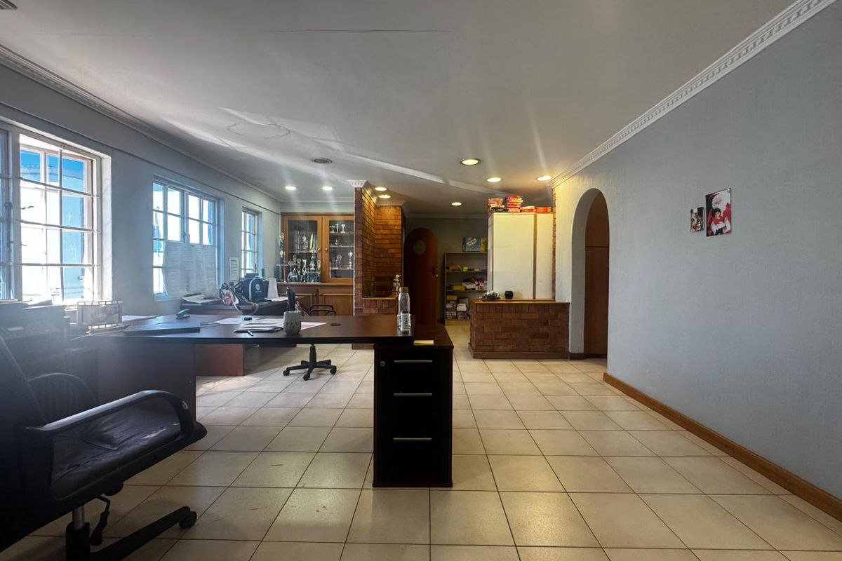 Spacious office area featuring tiled flooring, recessed lighting, crown molding, and a distinctive brick partition wall, offering a functional workspace layout.