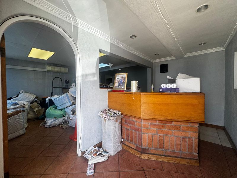 Reception area featuring a built-in brick and timber desk, tiled flooring, and decorative ceiling cornicing, providing a functional entry point for the industrial property.