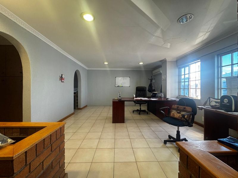 Spacious office area featuring tiled flooring, recessed lighting, and distinctive archways, providing a functional workspace within an industrial property setting.