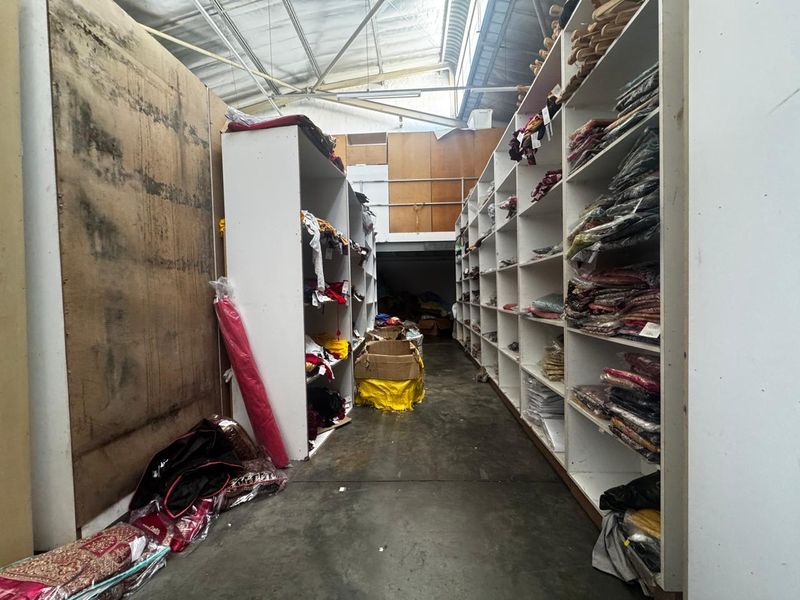 Industrial utility or storage space featuring extensive built-in shelving, concrete flooring, and an exposed roof structure with a mezzanine level.