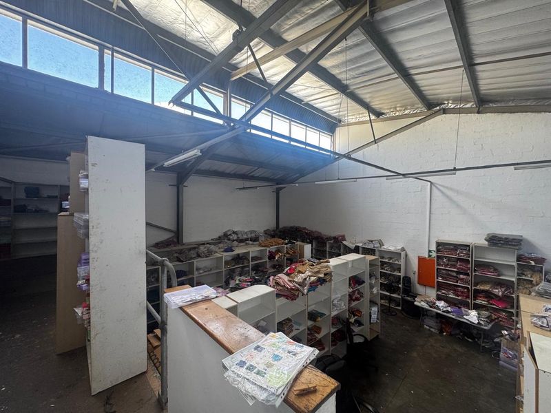 Industrial utility space featuring high ceilings with exposed steel trusses, clerestory windows for natural light, and extensive built-in shelving units.