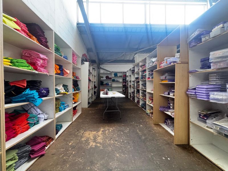 Industrial storage or utility space featuring extensive built-in shelving units, high-bay ceilings, and natural light from clerestory windows.