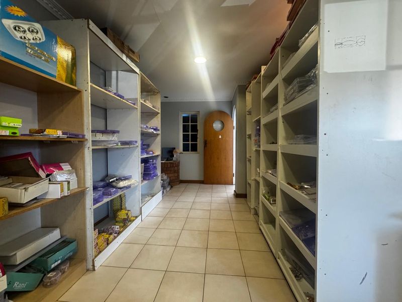 A functional utility or storage space featuring extensive built-in shelving, tiled flooring, and a solid timber entrance door.