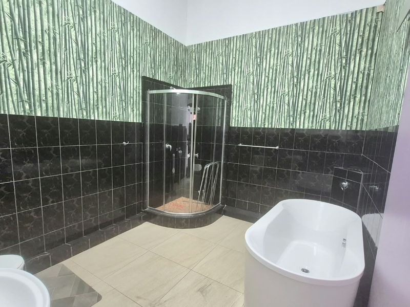 Bathroom featuring a corner shower enclosure, a freestanding bathtub, and tiled flooring, currently requiring cosmetic updates to the wall finishes.
