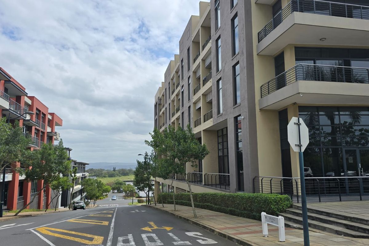 Street view of a modern multi-story office complex featuring glass facades, balconies, and well-maintained landscaping in a professional business park setting.