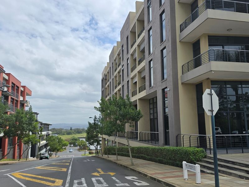 Street view of a modern multi-story office complex featuring glass facades, balconies, and well-maintained landscaping in a professional business park setting.