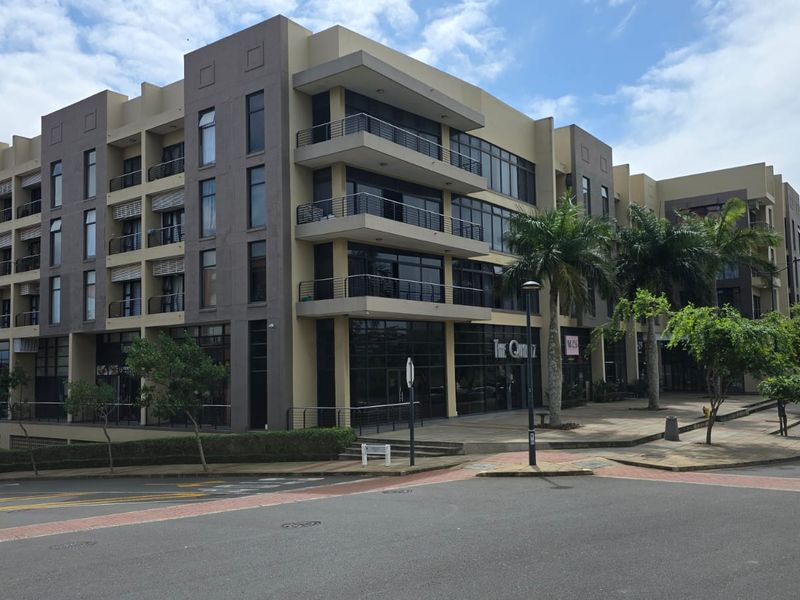 A modern multi-story office building featuring a contemporary facade with large glass windows, private balconies, and a well-maintained paved pedestrian entrance area.