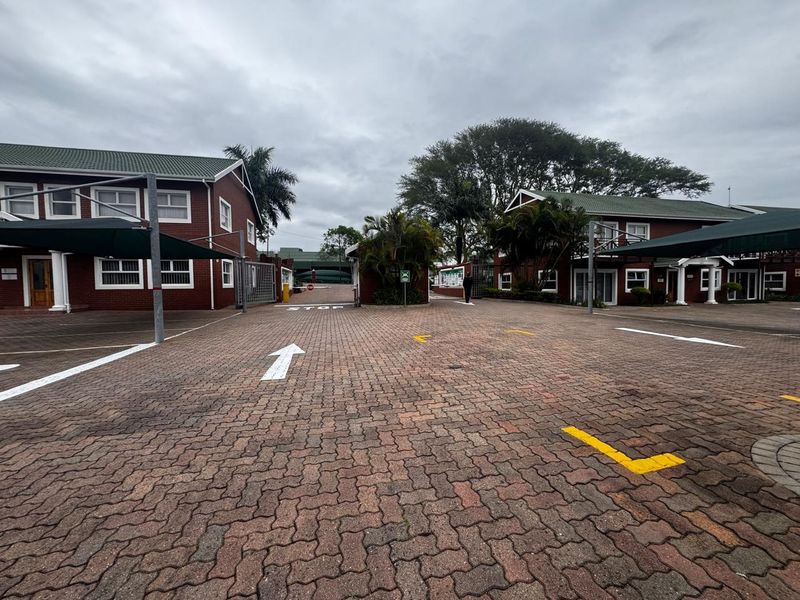 Exterior view of an office complex featuring a paved parking area with shade cloth carports and brick building facades.