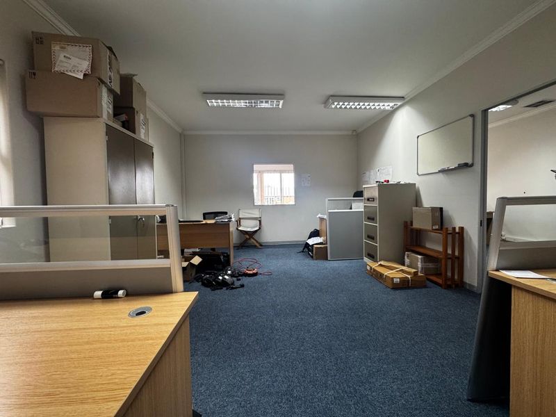 A functional office space featuring carpeted flooring, fluorescent lighting, and built-in storage, providing a practical environment for professional work.