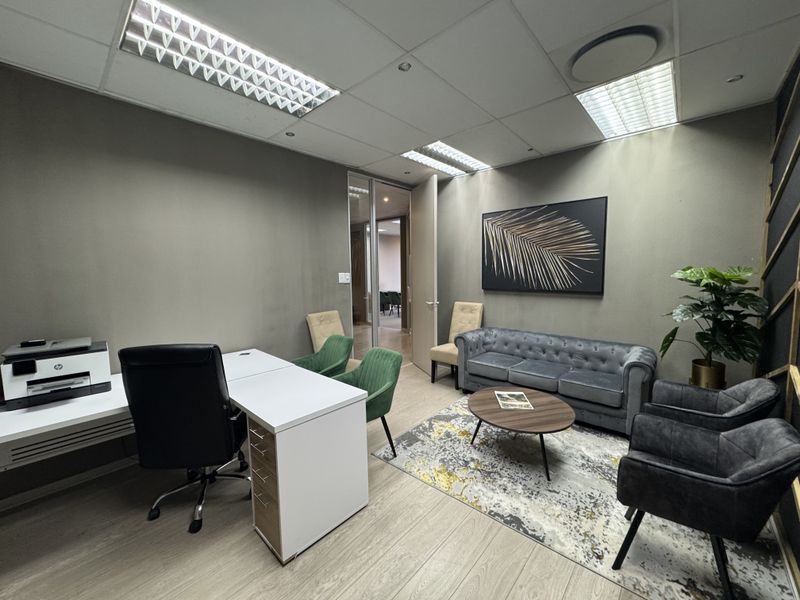 A professional office space featuring laminate flooring, recessed lighting, and a glass-paneled door, providing a functional and modern work environment.