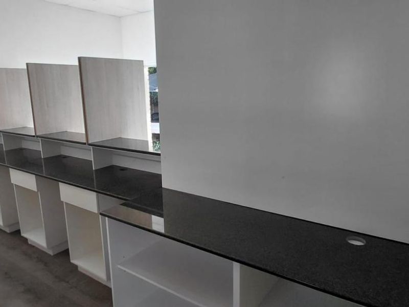 A clean, modern office space featuring built-in desks with dark stone countertops and integrated partition dividers, ideal for a professional workspace.