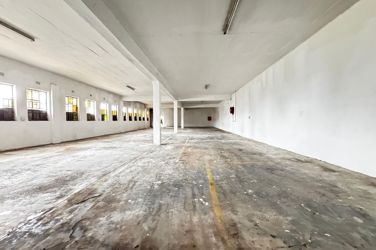 Expansive industrial utility space featuring high ceilings, concrete flooring, support columns, and multiple windows, suitable for storage or workshop use.