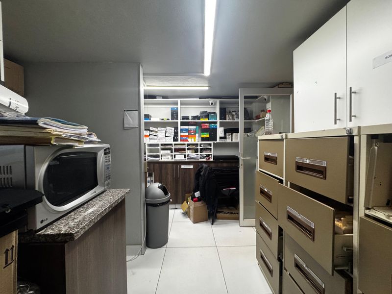 A functional utility and storage space featuring built-in cabinetry, shelving units, and tiled flooring, suitable for office or retail back-of-house operations.