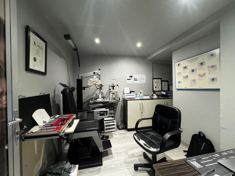 A functional optometry examination room featuring built-in cabinetry, recessed lighting, and durable laminate flooring, designed for clinical use.
