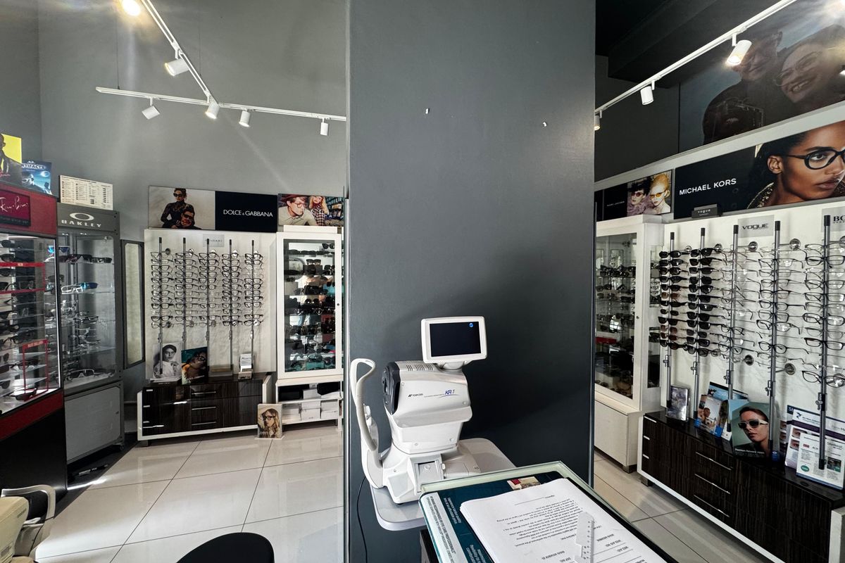 A well-maintained retail optical store interior featuring professional track lighting, tiled flooring, and extensive built-in wall-mounted eyewear display cabinetry.