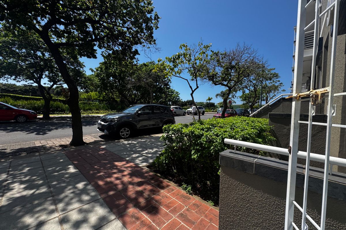 A street-level view showing the exterior walkway, paved access, and security features of the property frontage.