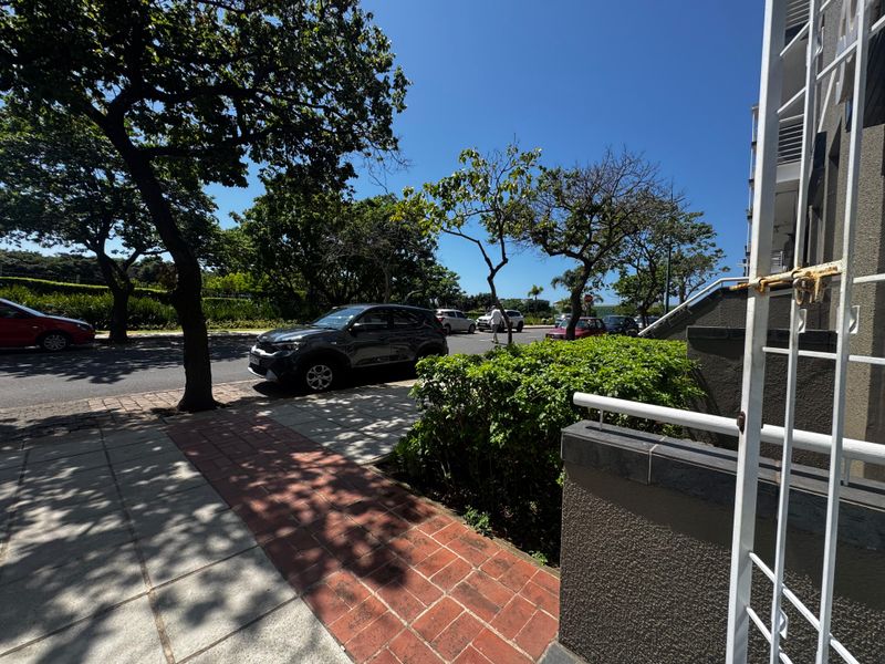 A street-level view showing the exterior walkway, paved access, and security features of the property frontage.