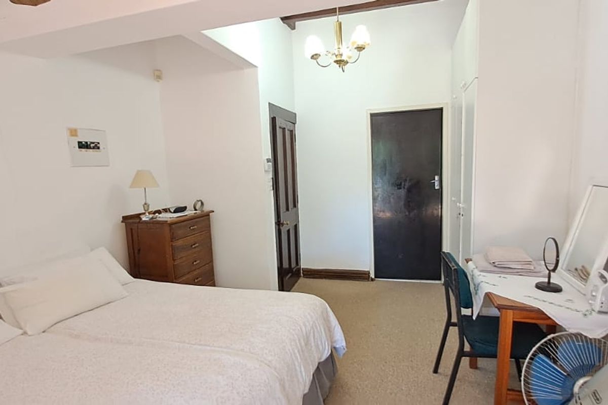 A functional bedroom featuring built-in cupboards, carpeted flooring, and a central ceiling light fixture.