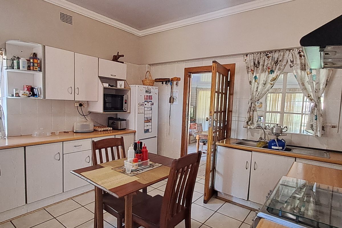 A functional kitchen featuring built-in cabinetry, laminate countertops, a gas hob, and tiled flooring, offering a practical layout with potential for modern updates.