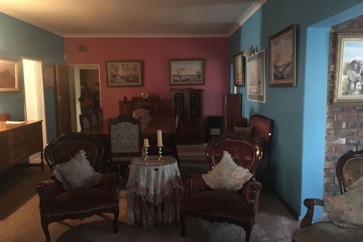 A spacious living and dining area featuring a brick fireplace and decorative coving, offering a traditional layout with potential for modern updates.