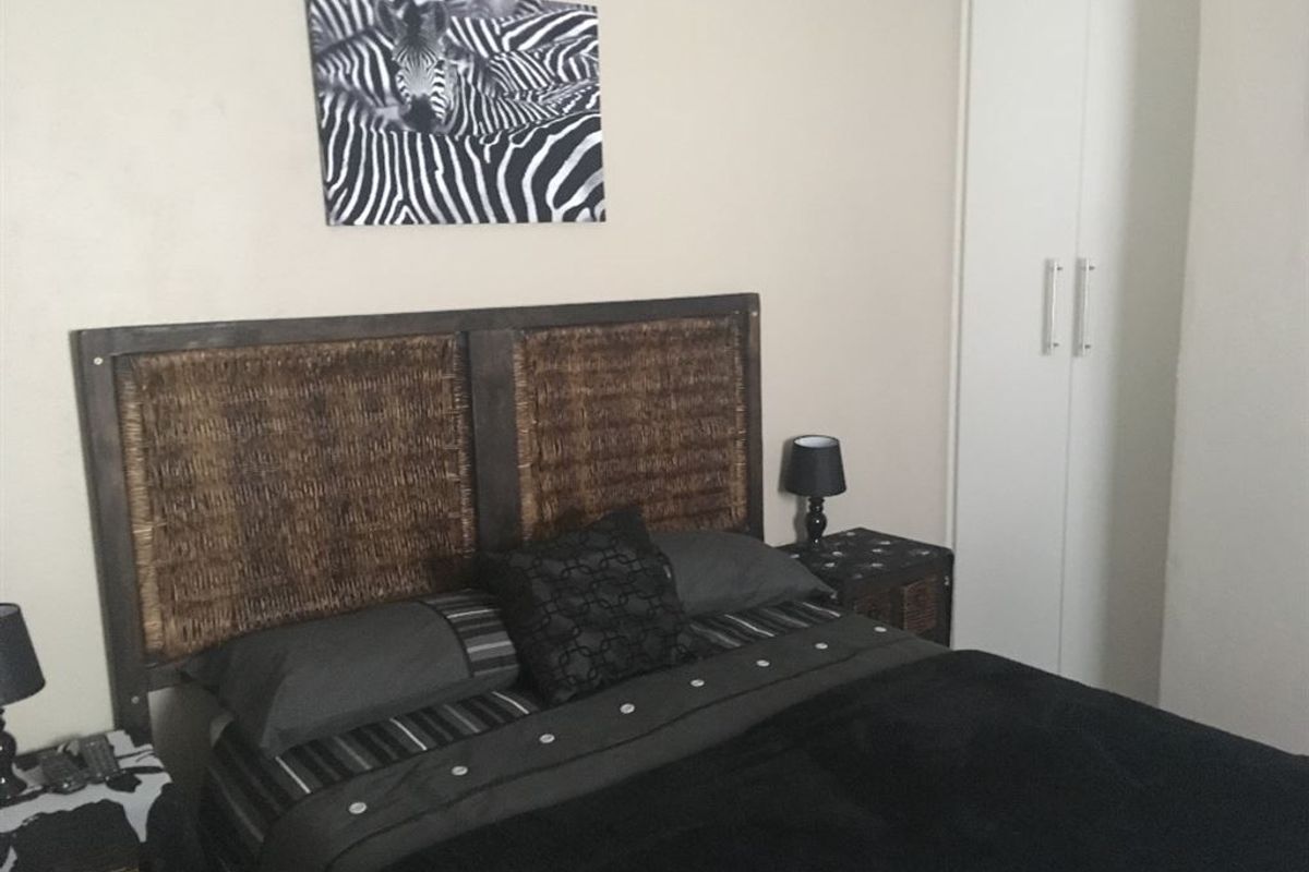 A bedroom featuring a built-in wardrobe with white cabinetry.