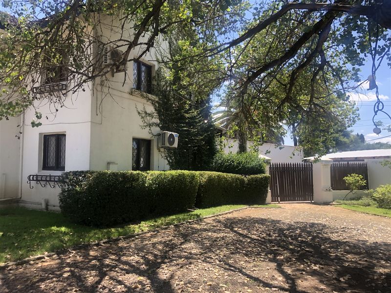 Front exterior view of the house featuring a driveway, timber gate, and established garden hedging.