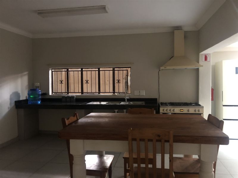 Functional kitchen featuring granite countertops, a gas hob with extractor fan, and tiled flooring, offering a practical layout for daily meal preparation.